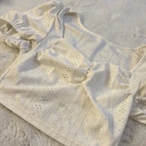 Vit blus från Shein - Säljer en söt vit blus från Shein med korta ärmar och ett fint broderat mönster. Blusen har en v-ringad design och elastiska detaljer vid ärmsluten. Perfekt för en somrig look!🩷