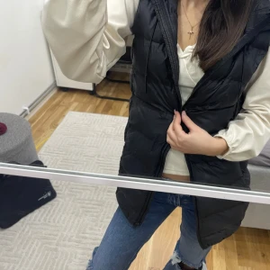 Svart dunväst från Zara  - Snygg svart dunväst med dragkedja, perfekt för kyligare dagar. Västen har en normal passform och är ett stilrent tillskott till garderoben.