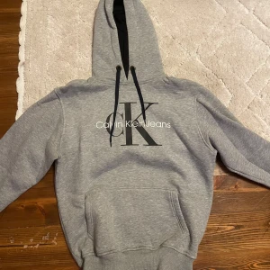 Grå hoodie Calvin Klein - Säljer en Calvin Klein hoodie som jag köpte utomlands för några år sedan. Väldigt fin och skön. Den är nopprig men kan nog fixas med tex rakhyvel