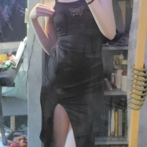 Brun klänning - En fin brun klänning med slit. Bak finns det snören som anpassar passformen och fram finns det en fin fjäril av "pärlor". Säljer då den inte passar mig längre. Använd en gång