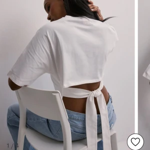 Vit kortärmad topp med knyt - Snygg vit topp med korta ärmar och knytning i ryggen. Perfekt för en avslappnad stil med en twist. Passar bra till jeans eller kjol.