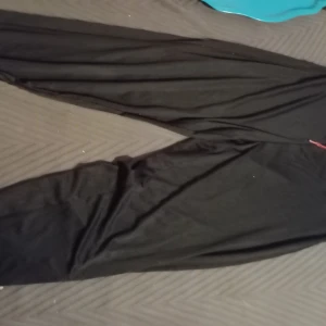 Svarta mjukisbyxor med snörning - Säljer ett par bekväma svarta mjukisbyxor med röd snörning i midjan. Perfekta för en avslappnad stil.