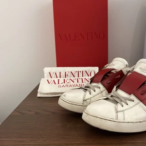 Valentino Garavani sneakers - Snygga Valentino Garavani sneakers i vitt och rött. Skorna är använda men har mycket kvar att ge! Innersulan är sliten men fortfarande väldigt bekväm och skicket är 7/10 