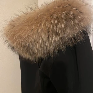 Svart subway dunjacka från märket hollies  - Säljer min snygga svarta subway dunjacka från Hollies med en lyxig äkta pälsdetalj runt kragen. Perfekt för kalla dagar med sin stilrena design och varma material. Använt i nyskick. Nypris 4000kr  Storlek 42 passar både M och L Rökfri jacka. Köpt från Hollies butiken.  Finns i Malmö men kan också frakta men köparen står för fraktkostnaden :) 