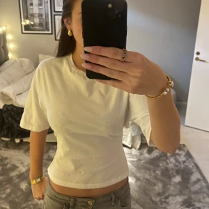 Vit kortärmad topp med rosett  - Snygg vit kortärmad topp med knyt i ryggen. Perfekt för en stilren och modern look. Passar bra till jeans eller kjol. Knappt använd!