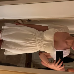 Vit klänning från NLY Trend - Säljer en söt vit klänning från Nelly med korta puffärmar och elastisk midja. Perfekt för sommarens varma dagar. Klänningen har en luftig passform och en mjuk, bekväm känsla. Aldrig använd. Köptes som studentklänning men valde en annan. Priset går att diskutera❤️ #student #studentklänning #vitklänning