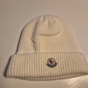 Vit ribbad mössa från Moncler - säljer en moncler mössa för att den inte passar mig köpte den på plick. han jag köpte den av hade kvitto men skicka inte det så vet ej om den är äkta.