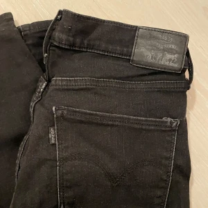 Svarta jeans från Levi's - Snygga svarta jeans från Levi's med klassisk design. De har en rak passform och är tillverkade i slitstarkt denim. Perfekta för en stilren look. Har vanligtvis M i byxor och dessa passar då, de är lite stretchiga i materialet. 