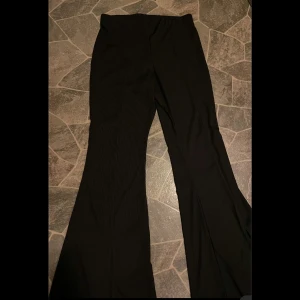 Svarta ribbade byxor från New Look - Snygga svarta ribbade byxor från New Look med en bootcut-stil. Perfekta för en stilren look med stretchigt material och slits längst ner på båda sidor🥰 Det står storlek 44 men de passar på mig som har M/L. 