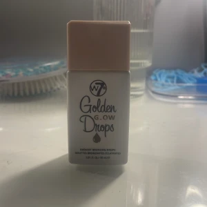 W7 Golden Glow Drops - W7 Golden Glow Drops är en flytande highlighter som ger en strålande och skimrande finish. Perfekt för att framhäva kindben och ge ansiktet en solkysst look. Kommer i en praktisk flaska med skruvlock.