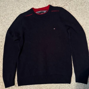 Tommy Hilfiger tröja  - Snygg svart tröja från Tommy Hilfiger med röd detalj vid halsringningen. 