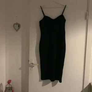 Svart axelbandslös klänning - Elegant svart klänning med smala axelband och figurnära passform. Perfekt för en stilren look.