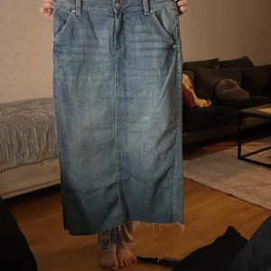 Blå jeanskjol från Divided - Snygg blå jeanskjol från Divided i storlek 38. Kjolen har en klassisk design med femficksmodell och en slits baktill för extra rörelsefrihet. Perfekt för en avslappnad stil. Kjolen har jag använd typ tre gånger. Den är fortfarande ny men så klart ingen prislapp.
