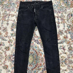 Svarta jeans från Dsquared2 - Snygga svarta jeans från Dsquared2 med 'ICON' patch på baksidan. De har en klassisk femficksdesign och en smal passform som ger en stilren look. Perfekta för dig som vill ha en trendig stil.