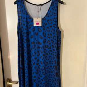 Blå leopardmönstrad klänning från Joseph Ribkoff - Snygg ärmlös klänning i blått med leopardmönster från Joseph Ribkoff. Perfekt för en djärv och trendig look. Klänningen har en rund halsringning och är tillverkad i ett mjukt material för extra komfort.