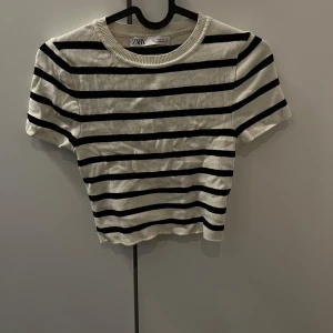 Randig kortärmad topp från Zara - Säljer en snygg randig topp från Zara i svart och vit. Den är kortärmad och har en rund halsringning. Perfekt för en stilren look.