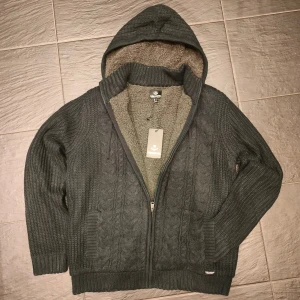 Pälsfodrad cardigan  - Säljer en mysig pälsfodrad cardigan. Den är mörkblå med grå päls på insidan, helt ny utan några som helst defekter. Sista bilden representerar färgen bättre! Skriv vid minsta fundering.