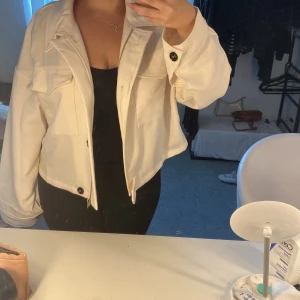 Beige kappa - Beige kappa med dragkedja och knappar, har även två stora fickor på framsidan 