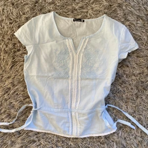 Vintage blouse - Fin baby blue färg, blus med broderier och snören på sidan så man kan dra åt. Storlek M på tröjan men motsvarar 36