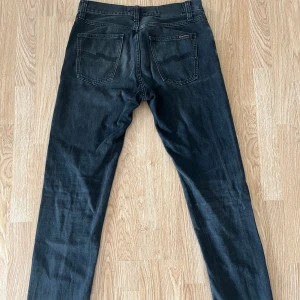 Svarta Nudie Jeans - Snygga Nudie Jeans till Salu! Säljer nu ett par riktigt stilrena Nudie jeans i svart, raka och med en klassisk passform. Perfekta för både vardag och fest! Passa på att fynda dessa trendiga jeans innan de försvinner! 👖🍾 Hör gärna av dig vid frågor.