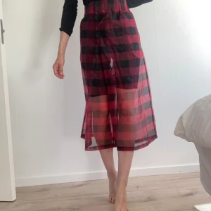 Rutig kjol i röd och svart - Säljer en superfin rutig kjol i röd och svart. Kjolen är lång och har en transparent look som ger en cool lager-på-lager-effekt. Perfekt för både vardag och fest! 🖤