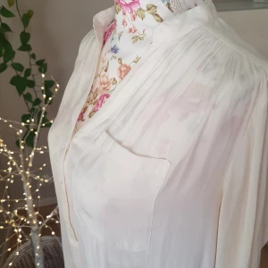Skir, söt blus i fint, lent tyg - Aldrig använd! Sval, skir blus m fina detaljer. Tyget har satinkänsla & är mönstrat m små rutor. (Hittat ett mystiskt liitet halv-hål vid knappslån, enl bild 5). ~ STOR rensning i min shop ~ Välj 5 för 100kr oavsett pris, skicka medd/lämna prisförsl 