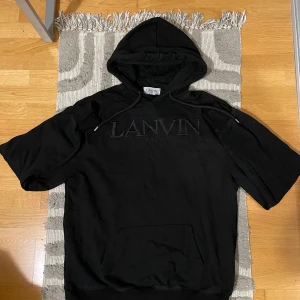 Lanvin Hoodie - Säljer en stilren svart hoodie från Lanvin med broderad logotyp på bröstet. Hoodien är perfekt för en grisch och avslappnad look. Känner dock att den gjort sitt och att det är sags för att separeras. Vid frågor så är det bara och ställa samt så är priset ej hugget i sten!(Lite skrynklig på bilden men kan lätt lösas av mig vid köp!)