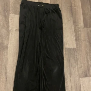 svarta mjukisbyxor med vida ben. perfekta för en avslappnad stil. - Snygga svarta byxor med vida ben och hög midja. Byxorna har en stilren design med två dekorativa öljetter i midjan. Perfekta för en chic och avslappnad look.