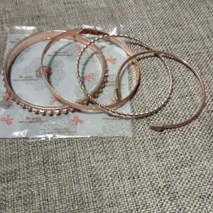 Set med guldarmband - Ett elegant set med flera guldarmband i olika stilar. Setet inkluderar ett armband med tvinnad design, ett med släta ytor och ett med dekorativa detaljer. Perfekt för att mixa och matcha för olika tillfällen.