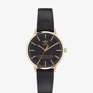 Svart och guld klocka från Adidas - Stilren klocka från Adidas med svart urtavla och guldfärgad boett. Klockan har ett svart skinnarmband och tydliga guldmarkeringar på urtavlan. Perfekt för den som gillar en klassisk och sportig look.