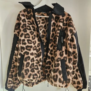Leopardmönstrad teddyjacka från Weekend Offender - Säljer en cool leopardmönstrad teddyjacka från Weekend Offender. Jackan har svarta detaljer och dragkedja framtill. Den är långärmad med en avslappnad passform och har en snygg kontrast mellan det fluffiga materialet och de svarta inslagen. Perfekt för att sticka ut i mängden!