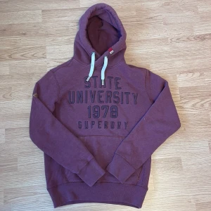 Vinröd hoodie från Superdry - Säljer en snygg unik vinröd hoodie från Superdry.   Den är i väldigt bra skick och passar dig som har Storlek S eller M. Tveka inte att skriva vid eventuell frågor/funderingar!😁💯