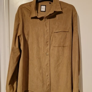 Beige overshirt  - Snygg beige overshirt i ett mjukt material. Den har har långa ärmar och en klassisk krage. Den är försedd med knappar framtill och en bröstficka för extra stil och funktionalitet.