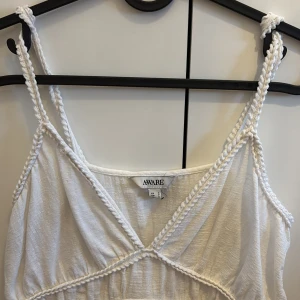 Vit linnetopp från Aware - Säljer en söt vit linnetopp från Aware med flätade axelband och v-ringad design. Toppen har en luftig passform och är perfekt för varma dagar. Och den är extremt lätt att styla på sommaren!