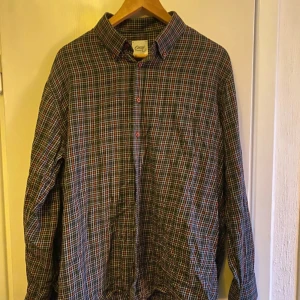 Rutig skjorta från Oscar of Sweden - Snygg rutig skjorta från Oscar of Sweden i flera färger som svart, vit och orange. Skjortan har långa ärmar och knappar framtill. Perfekt för en stilren look.