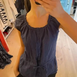 Marinblå blus - Säljer en söt marinblå blus med knappar framtill och ett knytning i midjan. Passar perfekt till sommaren eller med en kofta över💞💞Bilden är lånad
