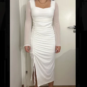Vit långärmad klänning med slits - Vit elegant långärmad klänning med slits från Cider. Aldrig använd (lappen är fortfarande på), är i storlek S. Perfekt för evenemang eller för student💕