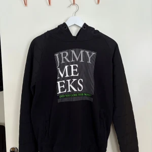 Svart hoodie från Jeremy Meeks  - Säljer en svart hoodie med tryck i vitt och grönt framtill. Hoodien har en klassisk design med långa ärmar och en bekväm passform. Perfekt för en avslappnad stil.