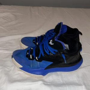 Blå och svarta Jordan zion  med loose Lace  - Snygga blå och svarta Jordan zion med vit sula och snörning. Perfekta för en sportig look med en cool design. De har en högre ankel och en stilren kombination av färger.