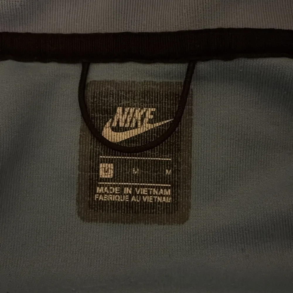 Säljer en snygg hoodie från Nike i blått och vitt med dragkedja och huva. Jackan har en ficka med dragkedja på ärmen och Nike-loggan på bröstet. Perfekt för en sportig look!. Neuletakit & Villapaidat.