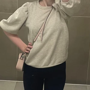 Beige tröja med puffärmar - Säljer en stilren glittrig beige tröja med puffärmar. Tröjan har en rund halsringning och är perfekt för en avslappnad look. Passar bra till både jeans och kjol.