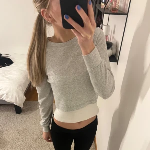 Grå croppad tröja - Säljer en stilren grå croppad tröja med långa ärmar. Perfekt för en avslappnad look. Tröjan är enkel och passar till många olika outfits.