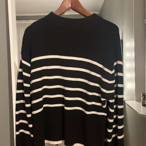 Svart och vit randig tröja - Säljer en stilren svart tröja med vita ränder. Tröjan har långa ärmar och en klassisk passform. Perfekt för en avslappnad look.