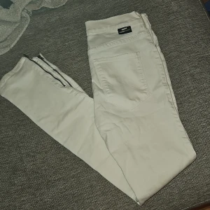 Vita jeans - Snygga vita jeans med en klassisk design. Byxorna har en dragkedja och knapp framtill samt fickor både fram och bak. Perfekta för en stilren look.