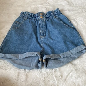 Blå jeansshorts från LAB Industries - Snygga blå jeansshorts från LAB Industries med elastisk midja och dubbla knappar framtill. Shortsen har uppvikta ben och praktiska fickor både fram och bak. Perfekta för en avslappnad stil. Säljer pågrund av att det aldrig kommer till användning 💕