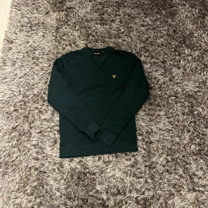 Mörkgrön tröja från Lyle & Scott - Säljer en stilren mörkgrön tröja från Lyle & Scott med deras ikoniska logga på bröstet. Tröjan har en klassisk passform med långa ärmar och ribbade muddar. Perfekt för en avslappnad stil. Storleken är XS
