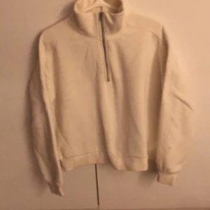 Vit tröja från 157 - Säljer en mysig vit fleece tröja från 157 med halv dragkedja och hög krage. Perfekt för kyliga dagar. Tröjan har långa ärmar och ribbade muddar vid ärmslut och nederkant. Tröjan är väldigt snygg tillsammans med ett par blå jeans!!😍 Som du kanske kan se på den sista bilden så är där en liten fläck men det går enkelt bort i tvätten💕💕