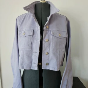 Ljuslila jacka från Carin Wester - Säljer en snygg ljuslila jacka från Carin Wester. Jackan är croppad med knappar framtill och har två bröstfickor med lock. Perfekt för en trendig look!