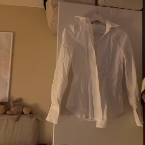 Vit skjorta som är figursydd  - En figursydd skjorta i storlek S. Helt ny. Behöver sälja då den e lite liten och hann ej lämna tillbaka. Jätte fin värkligen.