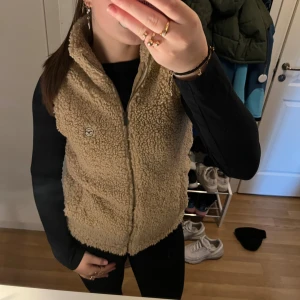 Beige teddyväst - Säljer en supermysig beige teddy väst med dragkedja. Västen har en normal passform och är idealisk för höst och vinter. storlek XS💗